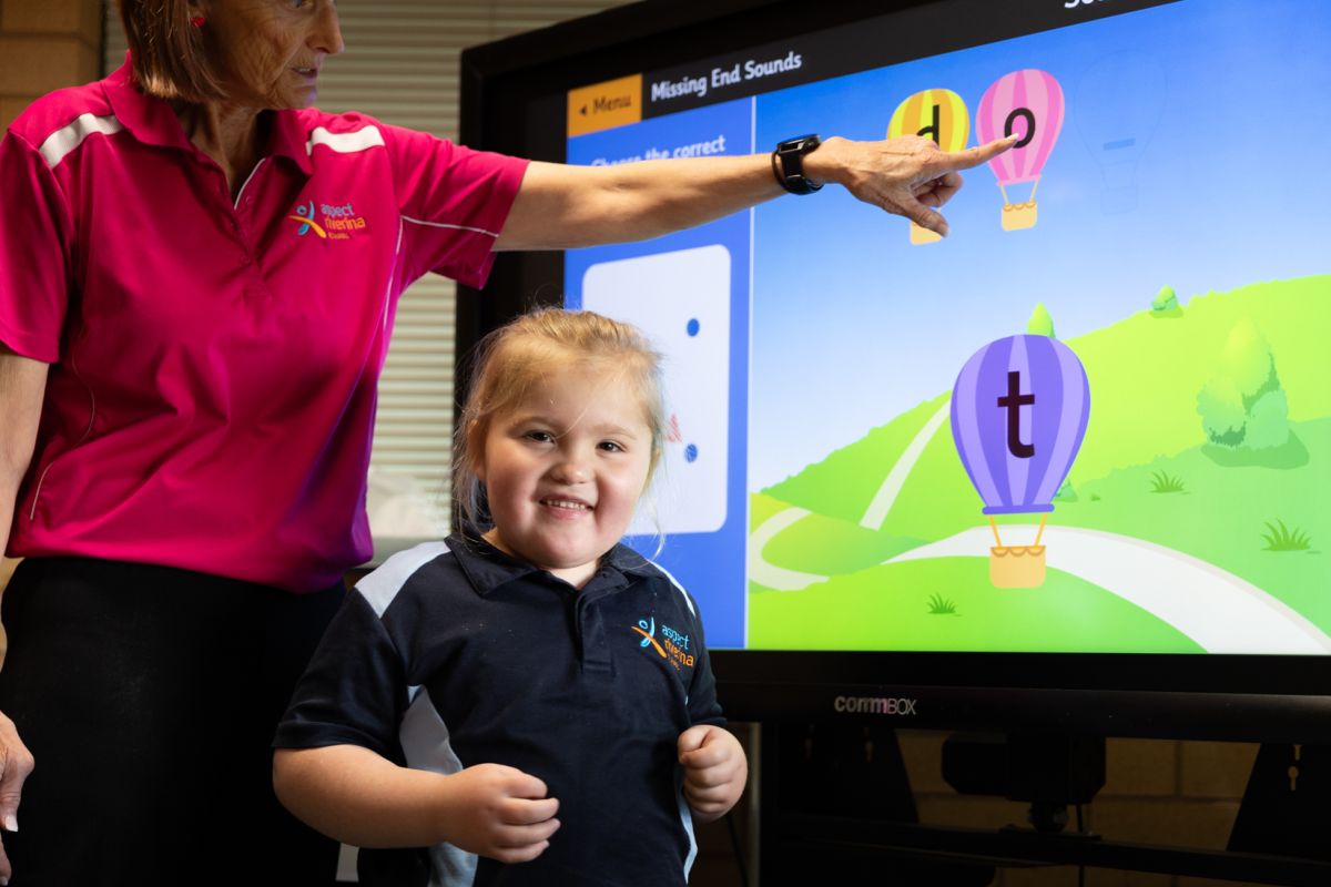A student smiling at the camera while using an interactive whiteboard